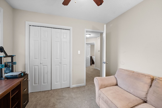 living area featuring light carpet, ceiling fan, and a textured ceiling