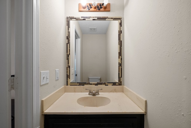 bathroom with vanity, toilet, and a textured ceiling