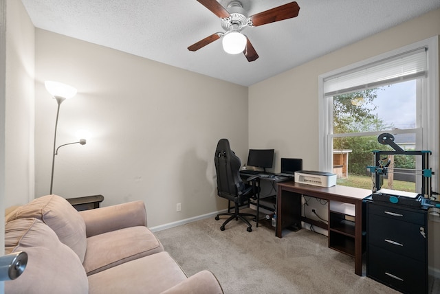 office space featuring ceiling fan, light colored carpet, a healthy amount of sunlight, and a textured ceiling