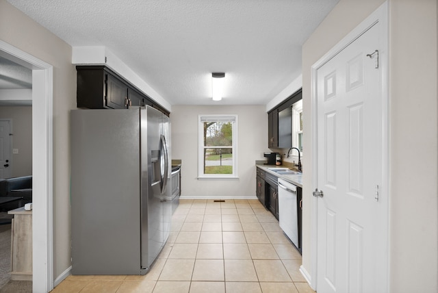 kitchen with a textured ceiling, light tile patterned flooring, sink, and stainless steel appliances