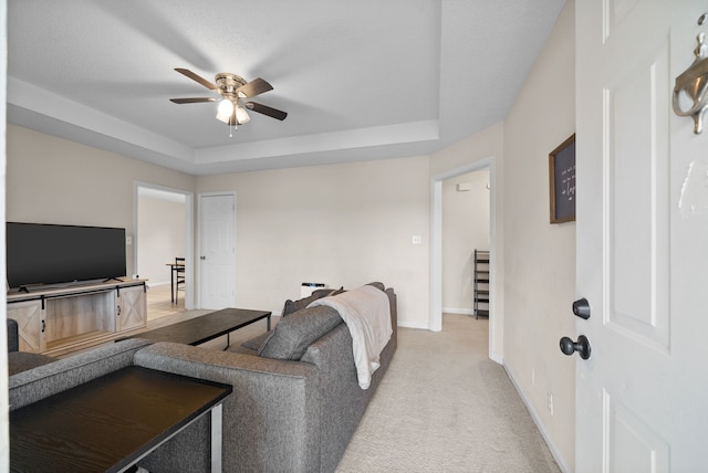 carpeted living room featuring ceiling fan and a raised ceiling