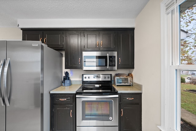 kitchen featuring a textured ceiling, stainless steel appliances, and plenty of natural light