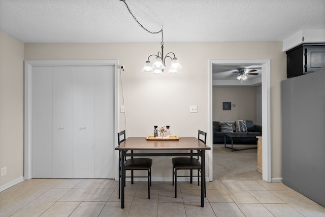 dining area with a textured ceiling, ceiling fan with notable chandelier, and light tile patterned floors