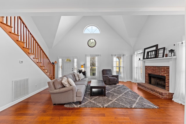 living room with a brick fireplace, high vaulted ceiling, and hardwood / wood-style flooring