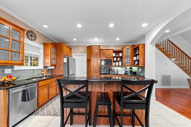 kitchen with sink, stainless steel appliances, a kitchen bar, decorative backsplash, and light wood-type flooring