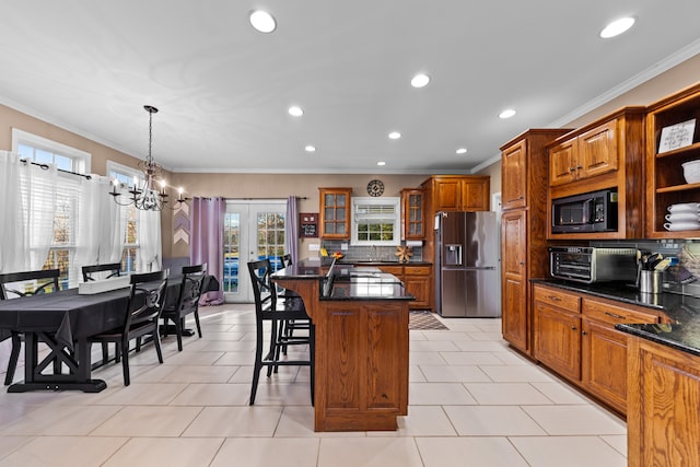 kitchen featuring stainless steel refrigerator with ice dispenser, a kitchen island, built in microwave, and a healthy amount of sunlight