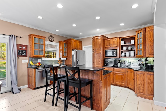 kitchen featuring a kitchen breakfast bar, backsplash, stainless steel appliances, dark stone countertops, and a kitchen island