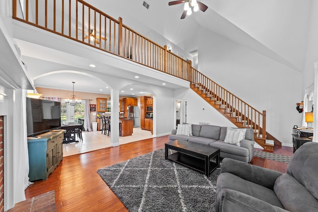 living room with hardwood / wood-style floors, high vaulted ceiling, and ceiling fan with notable chandelier