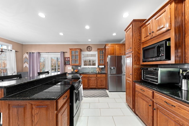 kitchen with sink, stainless steel appliances, backsplash, dark stone counters, and light tile patterned floors