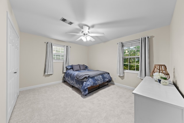 carpeted bedroom with ceiling fan, a closet, and multiple windows