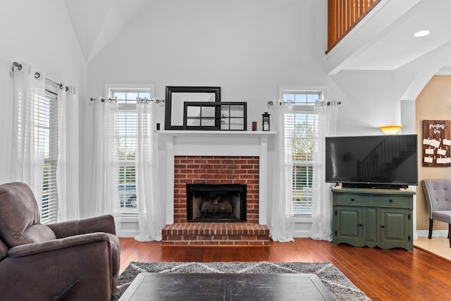 living room featuring a healthy amount of sunlight, wood-type flooring, and a brick fireplace