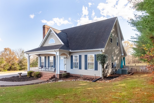 view of front facade with cooling unit, covered porch, and a front lawn