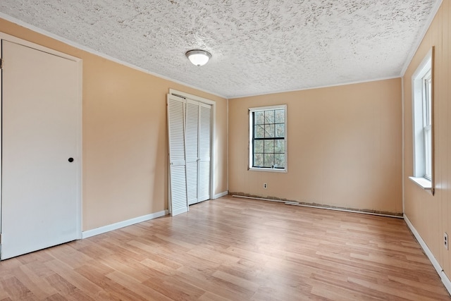 unfurnished bedroom featuring a textured ceiling, light wood-type flooring, and ornamental molding