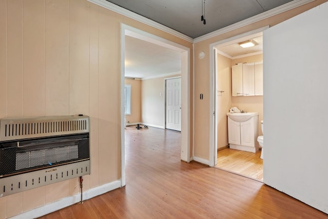 corridor featuring heating unit, light hardwood / wood-style flooring, and ornamental molding