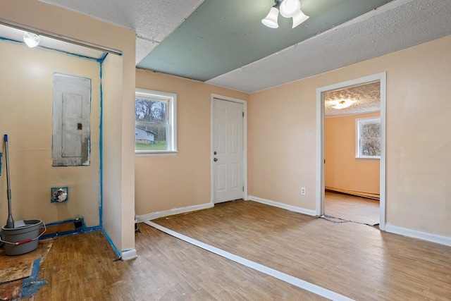 foyer entrance with light hardwood / wood-style floors, electric panel, and a baseboard radiator