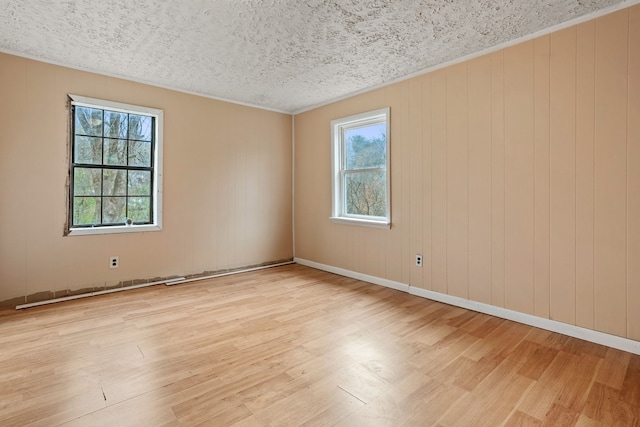 empty room with wood walls, light hardwood / wood-style floors, and a textured ceiling