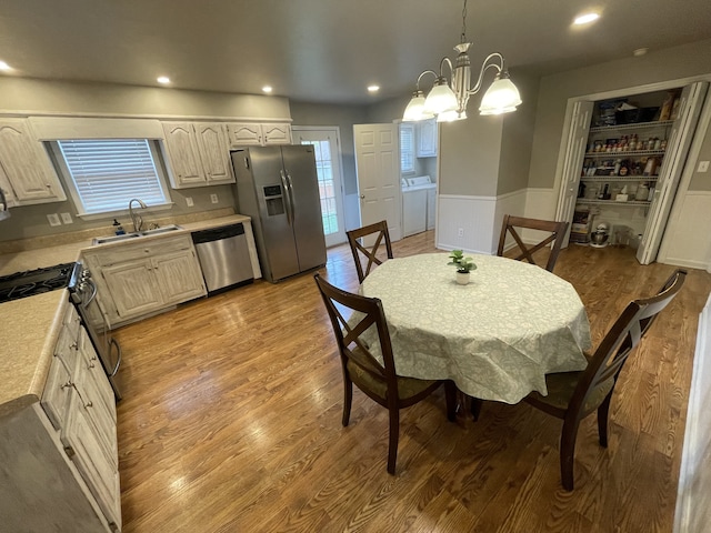 dining room featuring light hardwood / wood-style flooring, washing machine and dryer, sink, and a chandelier