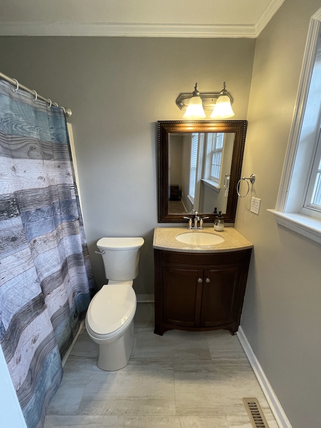 bathroom with toilet, vanity, and ornamental molding