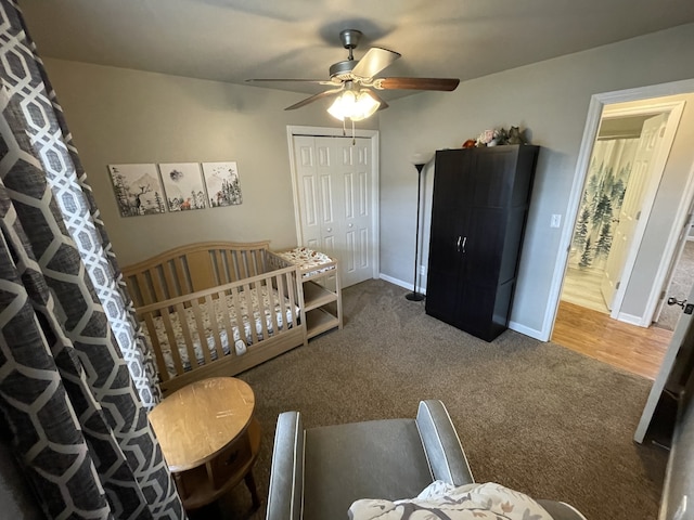 carpeted bedroom with ceiling fan, a closet, and a crib