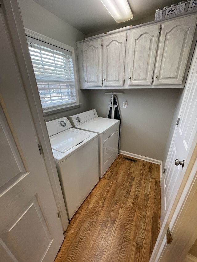 laundry area with cabinets, light wood-type flooring, and independent washer and dryer