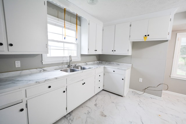 kitchen featuring a textured ceiling, white cabinetry, a wealth of natural light, and sink