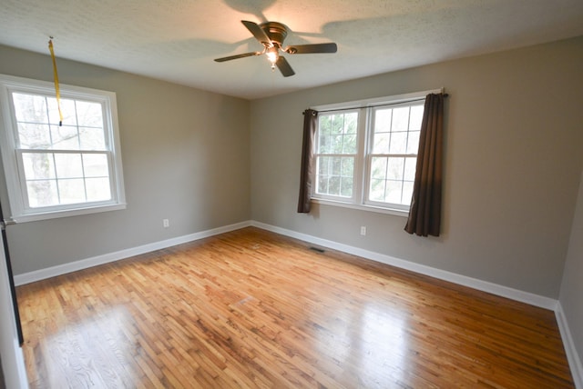 empty room with ceiling fan, light hardwood / wood-style flooring, a healthy amount of sunlight, and a textured ceiling