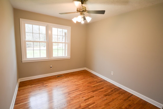 spare room with ceiling fan, light wood-type flooring, and a textured ceiling