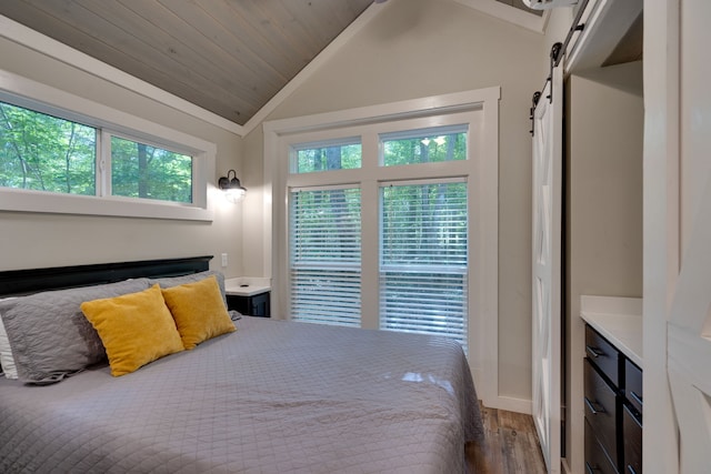 bedroom with hardwood / wood-style flooring, a barn door, wood ceiling, and vaulted ceiling