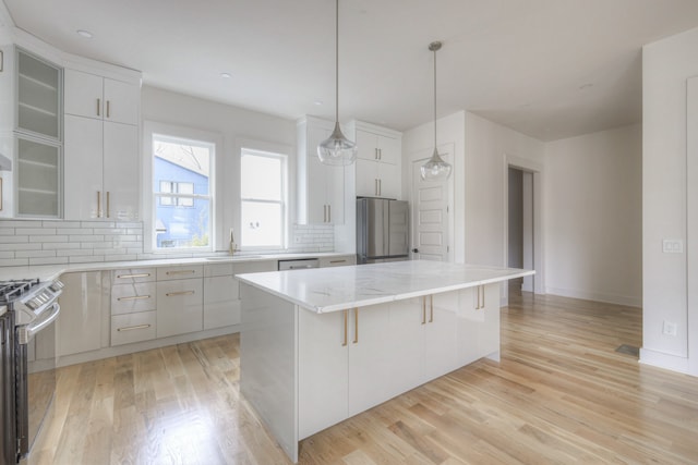 kitchen featuring white cabinetry, a center island, a kitchen breakfast bar, light hardwood / wood-style flooring, and appliances with stainless steel finishes