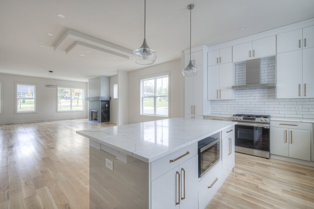 kitchen featuring white cabinets, stainless steel appliances, wall chimney range hood, and a kitchen island