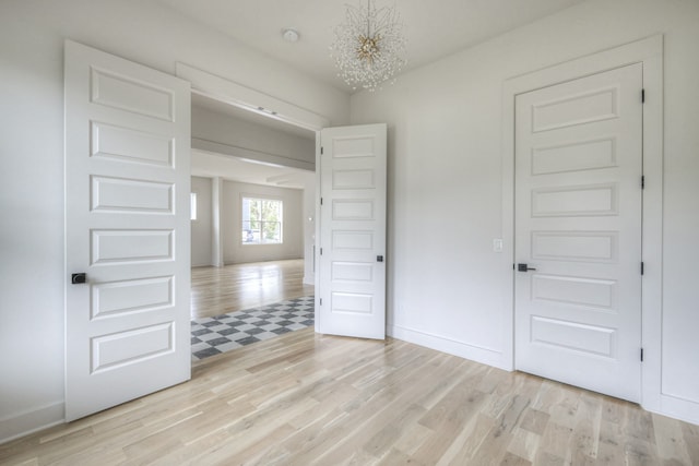 unfurnished bedroom featuring light wood-type flooring and a notable chandelier