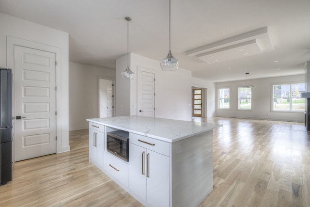 kitchen featuring white cabinets, decorative light fixtures, a center island, and built in microwave