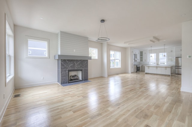 unfurnished living room with a tile fireplace and light hardwood / wood-style floors