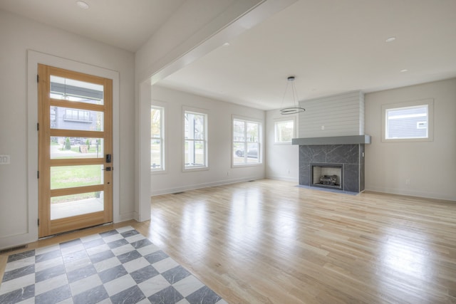 unfurnished living room with a fireplace, a healthy amount of sunlight, and light hardwood / wood-style floors