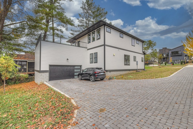 rear view of house with a lawn, a garage, and a balcony