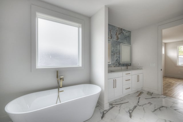 bathroom with hardwood / wood-style flooring, vanity, and a tub to relax in