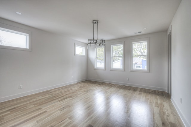 unfurnished room with light hardwood / wood-style floors and an inviting chandelier