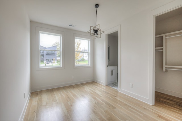 unfurnished bedroom featuring light wood-type flooring and a chandelier