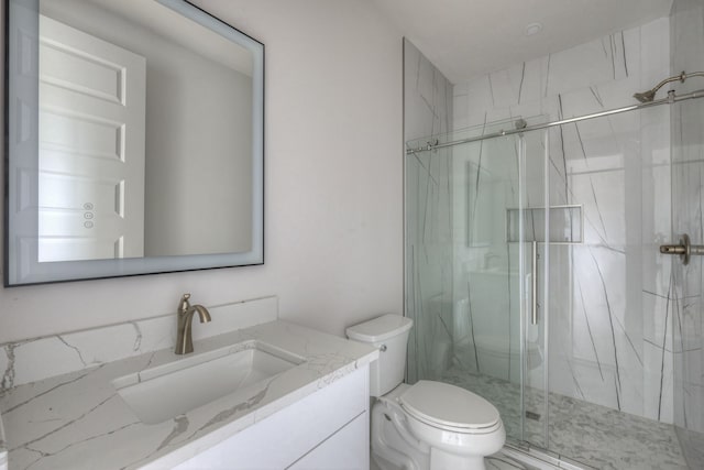 bathroom featuring a shower with door, vanity, and toilet