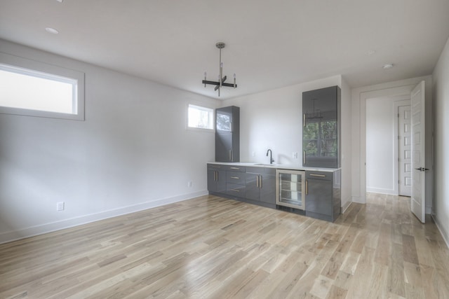 bar with wine cooler, light hardwood / wood-style flooring, and sink