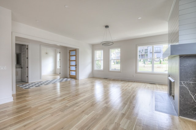 unfurnished living room featuring light wood-type flooring and a fireplace