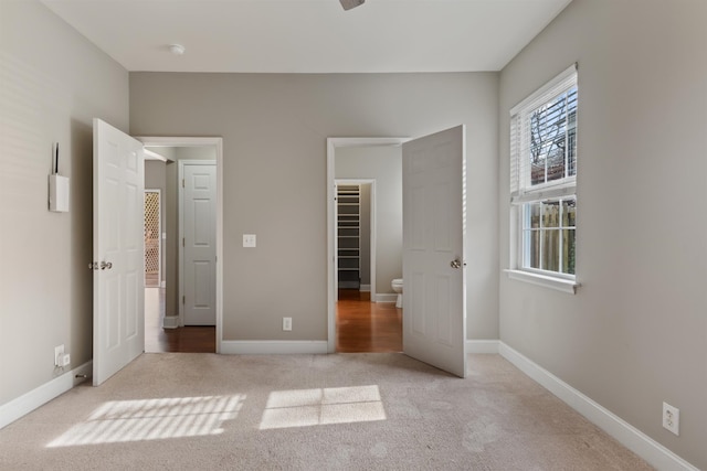 unfurnished bedroom with light colored carpet, a spacious closet, and a closet