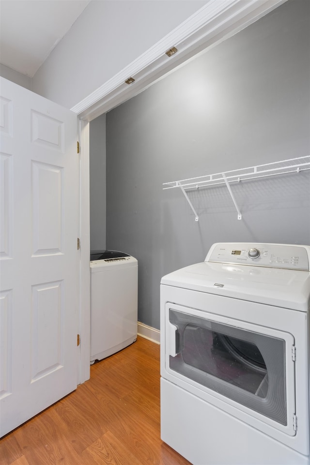 laundry room with independent washer and dryer and light hardwood / wood-style flooring