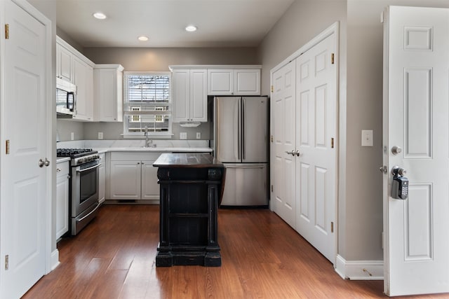 kitchen featuring white cabinetry, sink, dark hardwood / wood-style flooring, a kitchen island, and appliances with stainless steel finishes