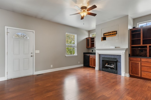 unfurnished living room with ceiling fan, dark hardwood / wood-style flooring, and a fireplace