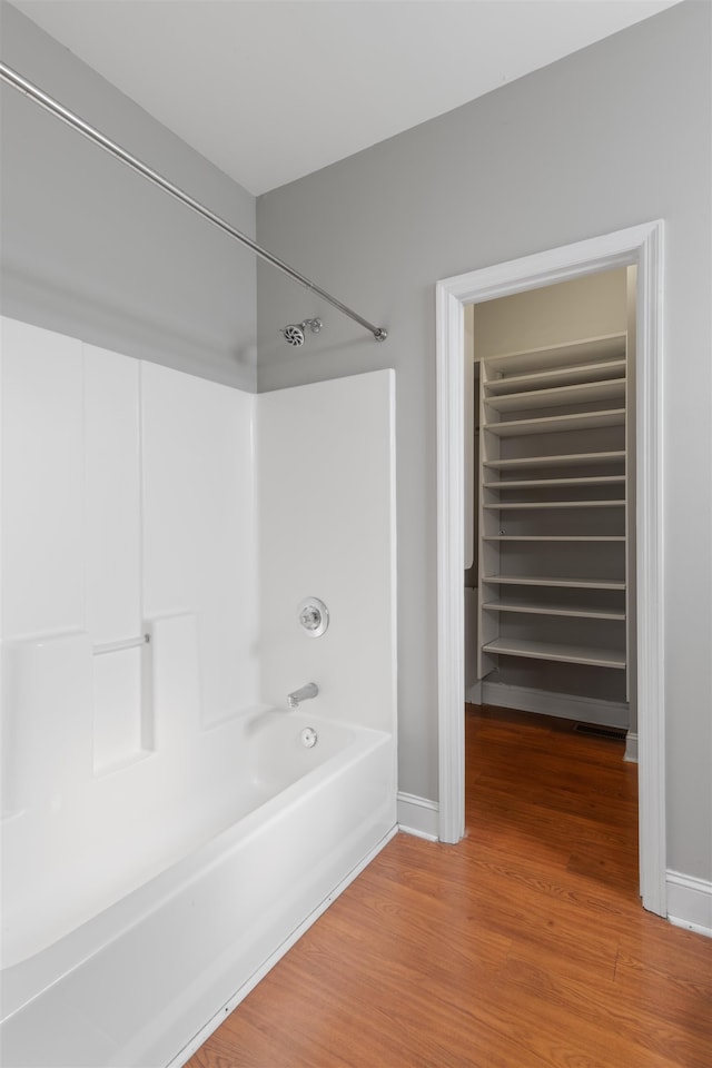 bathroom with hardwood / wood-style flooring, washtub / shower combination, and radiator heating unit