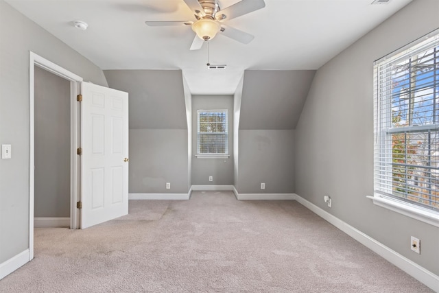 additional living space with ceiling fan, plenty of natural light, light colored carpet, and vaulted ceiling