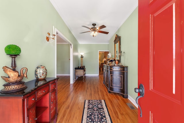 entrance foyer featuring light wood-type flooring, ceiling fan, and crown molding