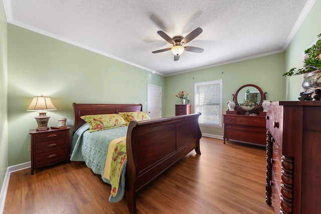 bedroom featuring ceiling fan, crown molding, wood-type flooring, and a textured ceiling