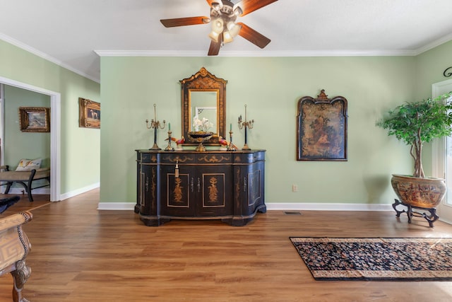 sitting room with wood-type flooring, ceiling fan, and crown molding